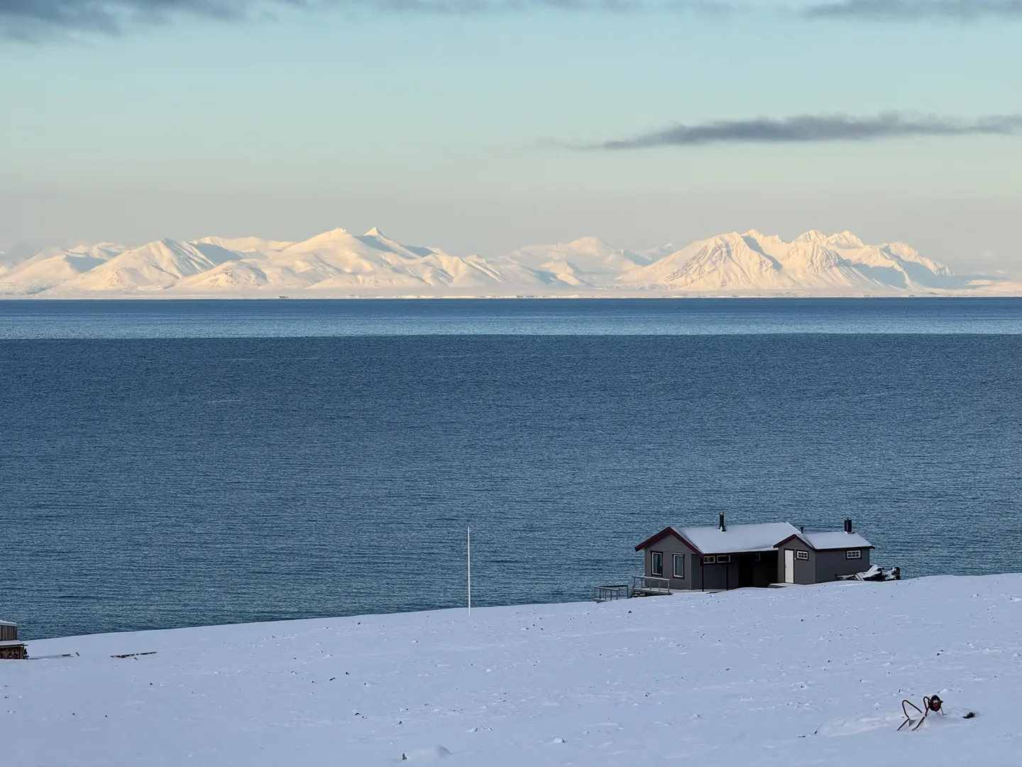 A cabin beside the fjord and snowy mountains
